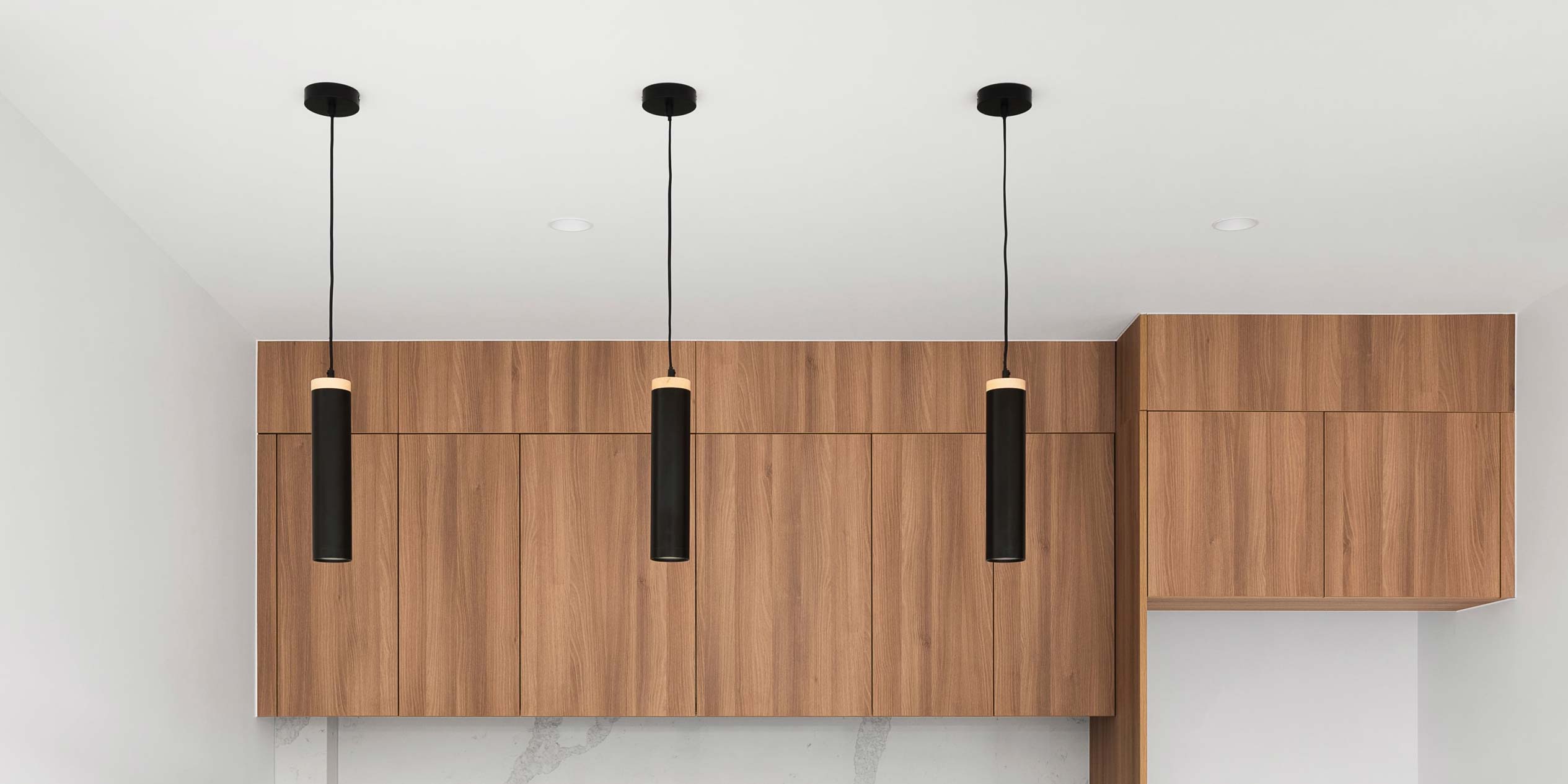 Cozy kitchen with wooden cabinets, recessed ceiling lights, and a staircase in the background.